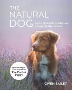 The cover of The Natural Dog features a soft focus of a light brown and white medium-sized dog standing in a field of lavender. 