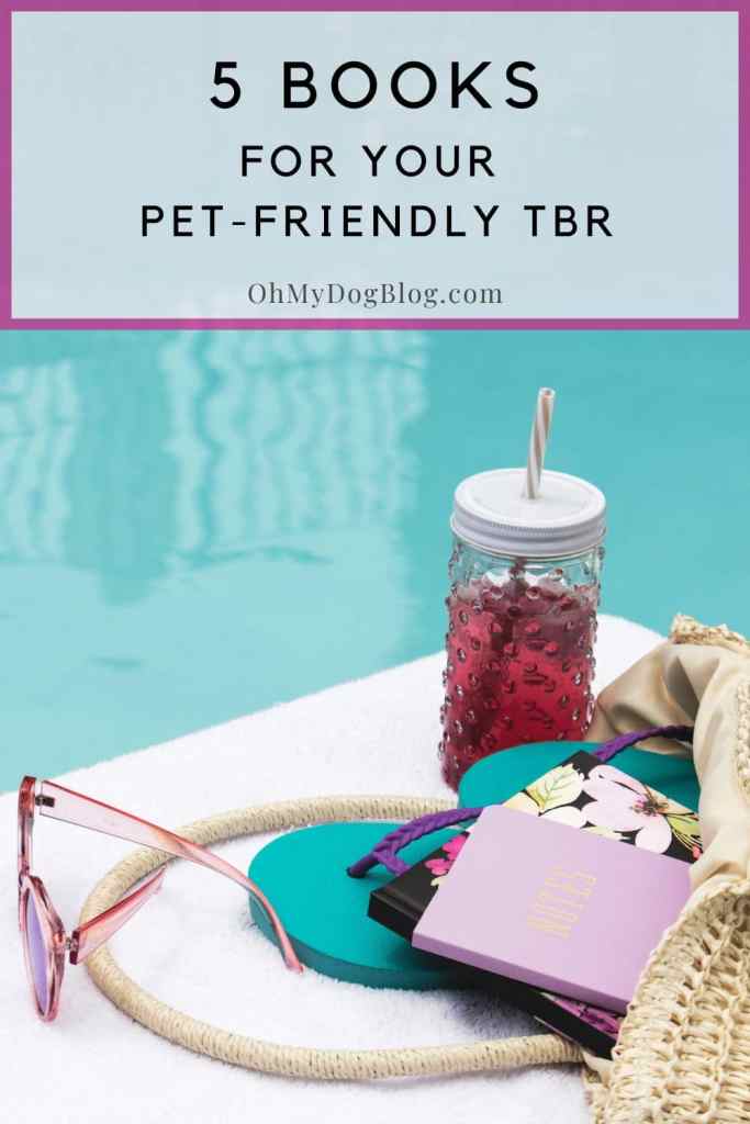 At the edge of a pool, on top of a white beach towel sits an iced tea drink in a glass container with a striped straw. Behind the beverage is a straw pool bag tipped over and the contents spill out onto the towel, including a pair of pink sunglasses, teal and purple flip flops, a hardback book with a  floral cover, and a pink notebook with Notes written in gold on the cover. The text overlay reads: 5 books for your pet-friendly TBR